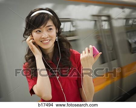 Teenage girl listening to mp3 player smiling View Large Photo Image Picture - Teenage girl listening to mp3 player smiling. Fotosearch