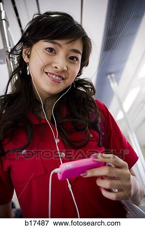 Teenage girl listening to mp3 player smiling View Large Photo Image Stock Photo - Teenage girl listening to mp3 player smiling. Fotosearch