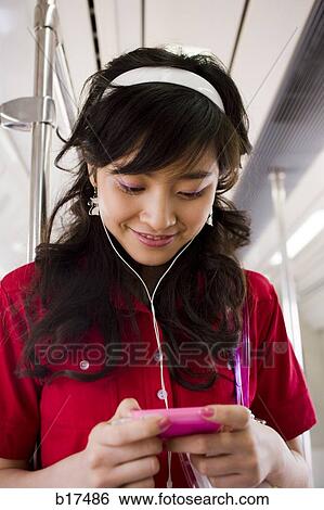 Teenage girl listening to mp3 player smiling View Large Photo Image Stock Photograph - Teenage girl listening to mp3 player smiling. Fotosearch