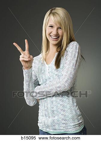 Teenage girl making peace sign and smiling View Large Photo Image Stock Photography - Teenage girl making peace sign and smiling. Fotosearch