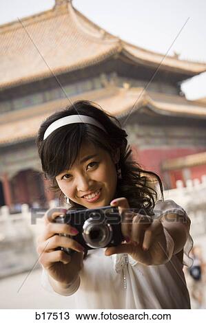 Teenage girl taking photograph outdoors with pagoda in background View Large Photo Image Stock Image - Teenage girl taking photograph outdoors with pagoda in background. Fotosearch