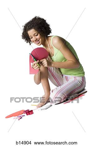 Teenage girl with braces and ear buds cutting out hearts with scissors View Large Photo Image Picture - Teenage girl with braces and ear buds cutting out hearts with scissors. Fotosearch
