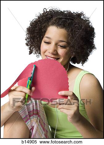 Teenage girl with braces and ear buds cutting out hearts with scissors View Large Photo Image Stock Photography - Teenage girl with braces and ear buds cutting out hearts with scissors. Fotosearch