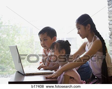 Stock Photo - Three children sitting in front of large window with laptop. Fotosearch