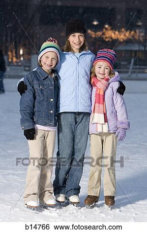 Stock Photograph - Three girls with skates outdoors in winter smiling. Fotosearch