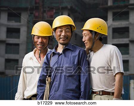 Three male construction workers with helmets outdoors smiling View Large Photo Image Stock Photo - Three male construction workers with helmets outdoors smiling. Fotosearch