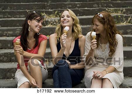 Three women sitting on steps outdoors eating ice cream cones smiling View Large Photo Image Stock Image - Three women sitting on steps outdoors eating ice cream cones smiling. Fotosearch