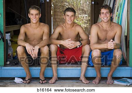 Picture - Three young men sitting outdoors. Fotosearch