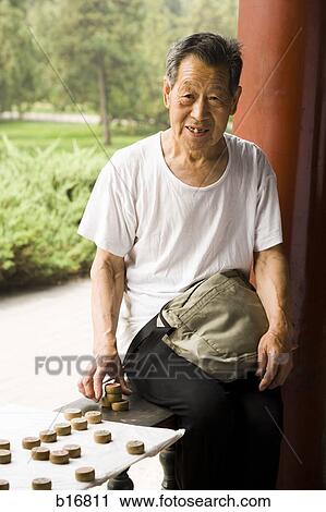 Stock Image - Toothless man sitting outdoors with board game. Fotosearch
