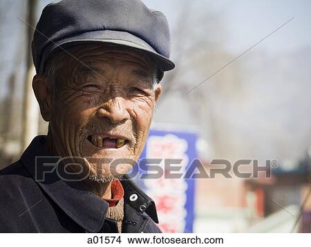 Picture - Toothless man with cap smiling outdoors. Fotosearch