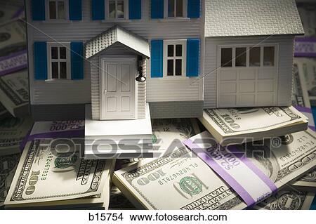 Picture - Toy house on pile of one hundred dollar bills. Fotosearch