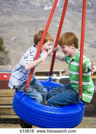 Two boys playing on tire swing outdoors View Large Photo Image Stock Photograph - Two boys playing on tire swing outdoors. Fotosearch