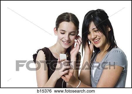 Two girls listening to mp3 player smiling View Large Photo Image Stock Photograph - Two girls listening to mp3 player smiling. Fotosearch