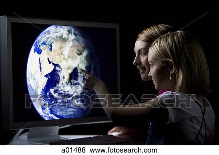 Two girls looking at earth on computer monitor View Large Photo Image Stock Photo - Two girls looking at earth on computer monitor. Fotosearch