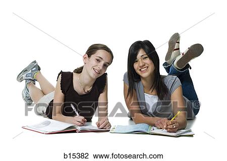 Stock Image - Two girls lying down doing homework. Fotosearch