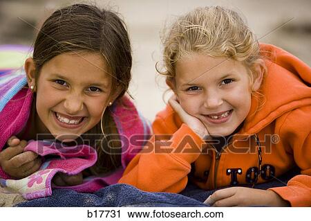 Two girls lying down on beach towels smiling View Large Photo Image Stock Image - Two girls lying down on beach towels smiling. Fotosearch