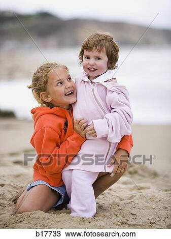 Two girls on beach embracing and smiling View Large Photo Image Stock Image - Two girls on beach embracing and smiling. Fotosearch