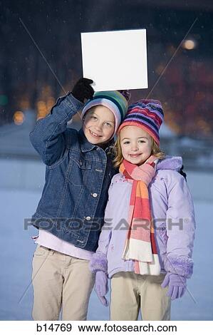 Two girls outdoors in winter with blank sign View Large Photo Image Stock Photo - Two girls outdoors in winter with blank sign. Fotosearch