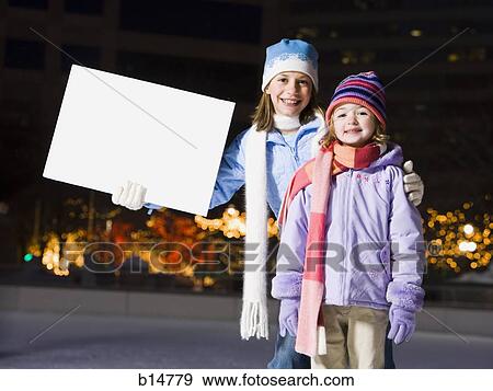 Two girls outdoors in winter with blank sign View Large Photo Image Stock Photo - Two girls outdoors in winter with blank sign. Fotosearch