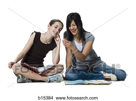 Two girls sitting cross legged with homework and mp3 player View Large Photo Image Picture - Two girls sitting cross legged with homework and mp3 player. Fotosearch
