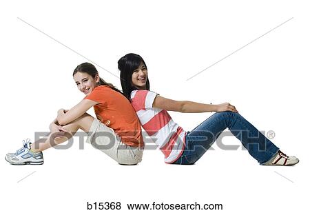 Stock Photo - Two girls sitting with backs together smiling. Fotosearch