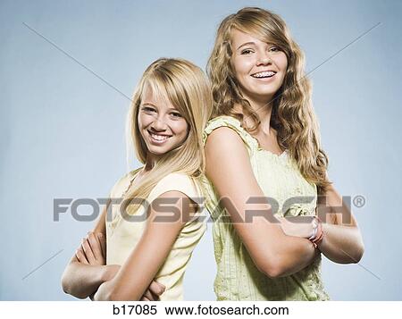 Two girls smiling with arms crossed back to back View Large Photo Image Stock Photography - Two girls smiling with arms crossed back to back. Fotosearch