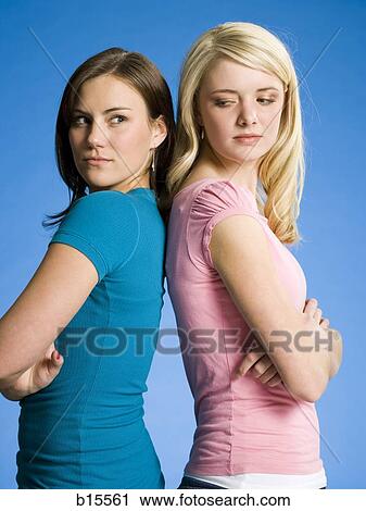 Two girls with arms crossed back to back scowling View Large Photo Image Stock Image - Two girls with arms crossed back to back scowling. Fotosearch