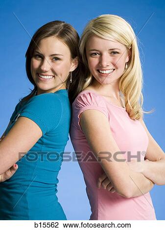 Two girls with arms crossed back to back smiling View Large Photo Image Stock Image - Two girls with arms crossed back to back smiling. Fotosearch