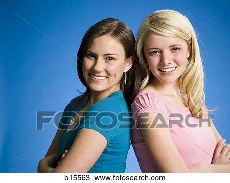 Two girls with arms crossed back to back smiling View Large Photo Image Stock Image - Two girls with arms crossed back to back smiling. Fotosearch