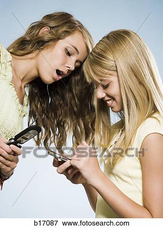 Two girls with cell phones smiling View Large Photo Image Stock Photo - Two girls with cell phones smiling. Fotosearch