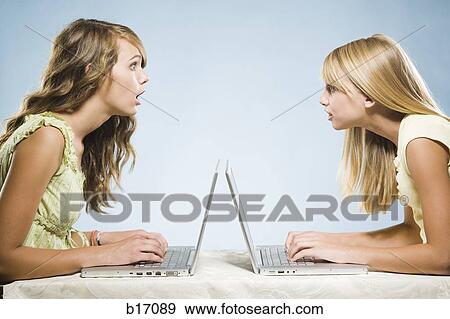 Two girls with laptops typing View Large Photo Image Stock Photo - Two girls with laptops typing. Fotosearch