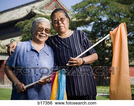 Two women embracing outdoors with flags and pagoda in background View Large Photo Image Stock Photograph - Two women embracing outdoors with flags and pagoda in background. Fotosearch
