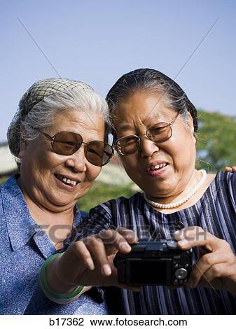 Two women embracing outdoors with camera smiling View Large Photo Image Stock Image - Two women embracing outdoors with camera smiling. Fotosearch