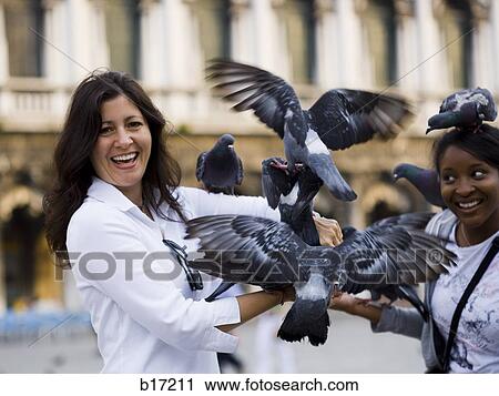 Two women in public square with pigeons laughing View Large Photo Image Stock Image - Two women in public square with pigeons laughing. Fotosearch