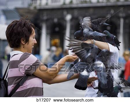 Stock Photo - Two women in public square with pigeons laughing. Fotosearch