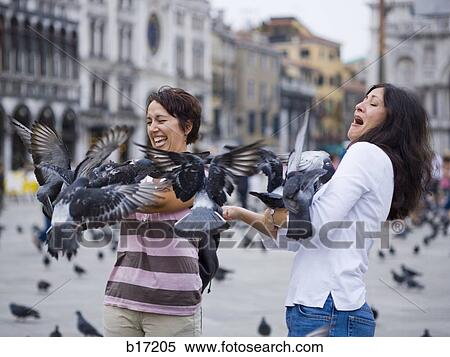 Two women in public square with pigeons laughing View Large Photo Image Stock Photography - Two women in public square with pigeons laughing. Fotosearch