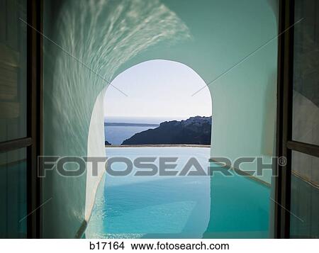 View of infinity pool through archway with mountains and water View Large Photo Image Picture - View of infinity pool through archway with mountains and water. Fotosearch