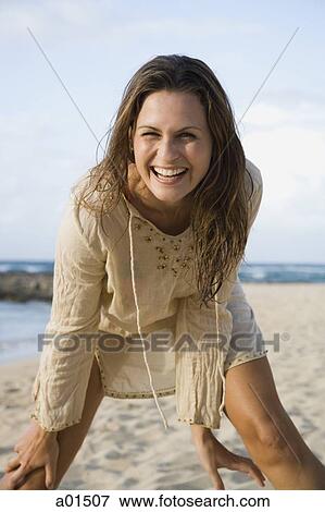 Stock Photo - Woman bending and smiling on beach. Fotosearch