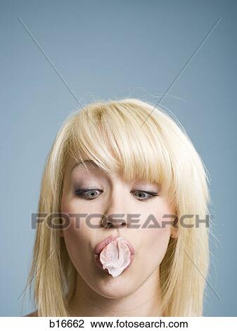 Stock Image - Woman blowing bubbles with chewing gum. Fotosearch