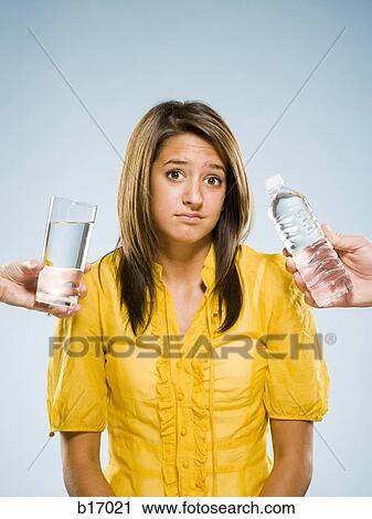 Woman choosing between glass of water and bottled water View Large Photo Image Stock Image - Woman choosing between glass of water and bottled water. Fotosearch
