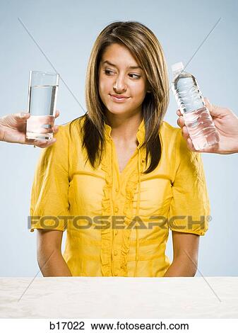 Woman choosing between glass of water and bottled water View Large Photo Image Stock Image - Woman choosing between glass of water and bottled water. Fotosearch