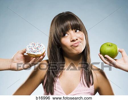 Woman deciding between a donut and green apple View Large Photo Image Stock Photograph - Woman deciding between a donut and green apple. Fotosearch