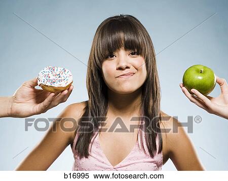 Woman deciding between a donut and green apple View Large Photo Image Stock Photography - Woman deciding between a donut and green apple. Fotosearch