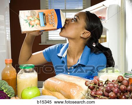 Woman drinking orange juice from carton in refrigerator with healthy foods View Large Photo Image Stock Photography - Woman drinking orange juice from carton in refrigerator with healthy foods. Fotosearch