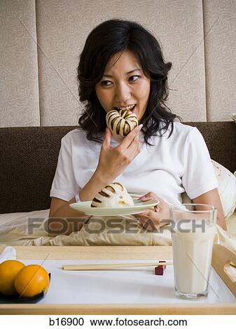 Woman eating breakfast in bed smiling View Large Photo Image Stock Image - Woman eating breakfast in bed smiling. Fotosearch