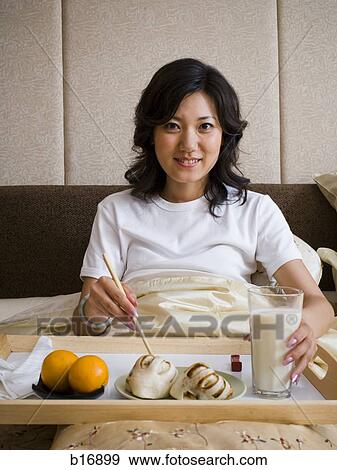 Woman eating breakfast in bed smiling View Large Photo Image Stock Photo - Woman eating breakfast in bed smiling. Fotosearch