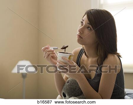 Woman eating chocolate ice cream in bed with stuffed animal View Large Photo Image Stock Photo - Woman eating chocolate ice cream in bed with stuffed animal. Fotosearch