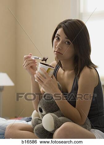 Woman eating chocolate ice cream in bed with stuffed animal View Large Photo Image Stock Photograph - Woman eating chocolate ice cream in bed with stuffed animal. Fotosearch