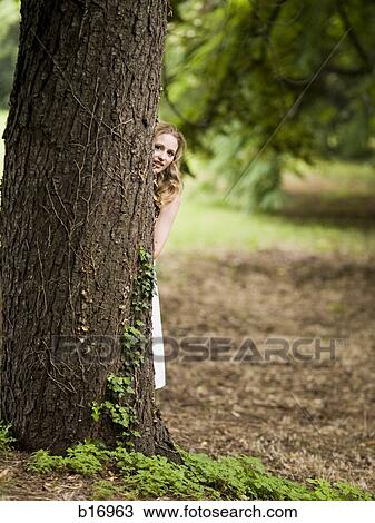 Stock Image - Woman hiding behind tree. Fotosearch