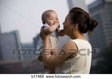 Woman holding baby outdoors smiling View Large Photo Image Stock Photo - Woman holding baby outdoors smiling. Fotosearch